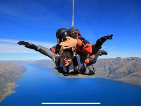 An areal view of Queenstown, with me in the middle skydiving. A man is attached to my back. 